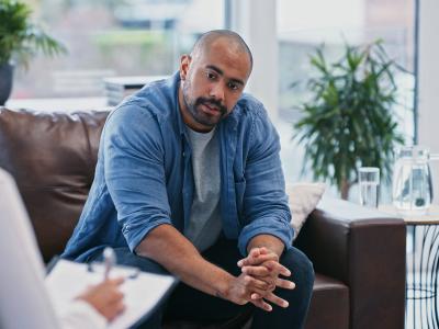 A man sits and talks to a woman holding a clipboard